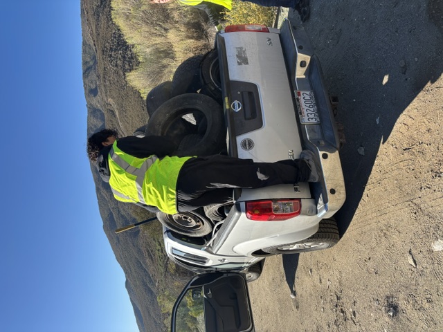 A volunteer in a safety vest loads tires into a pickup truck