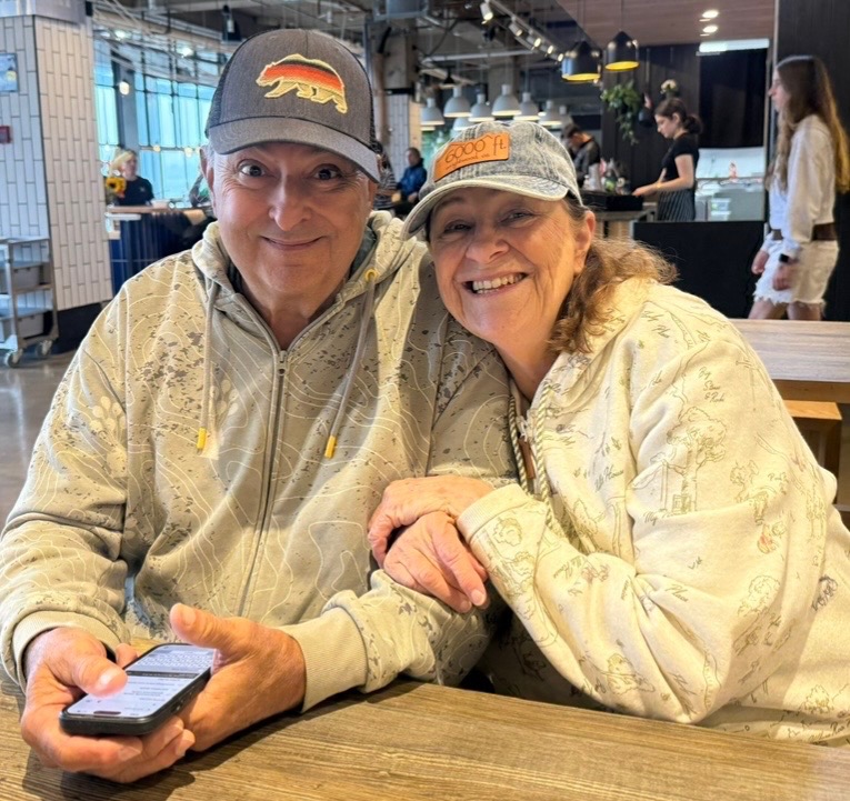 Russ Drew and his wife Linda smiling together at a table, arm in arm