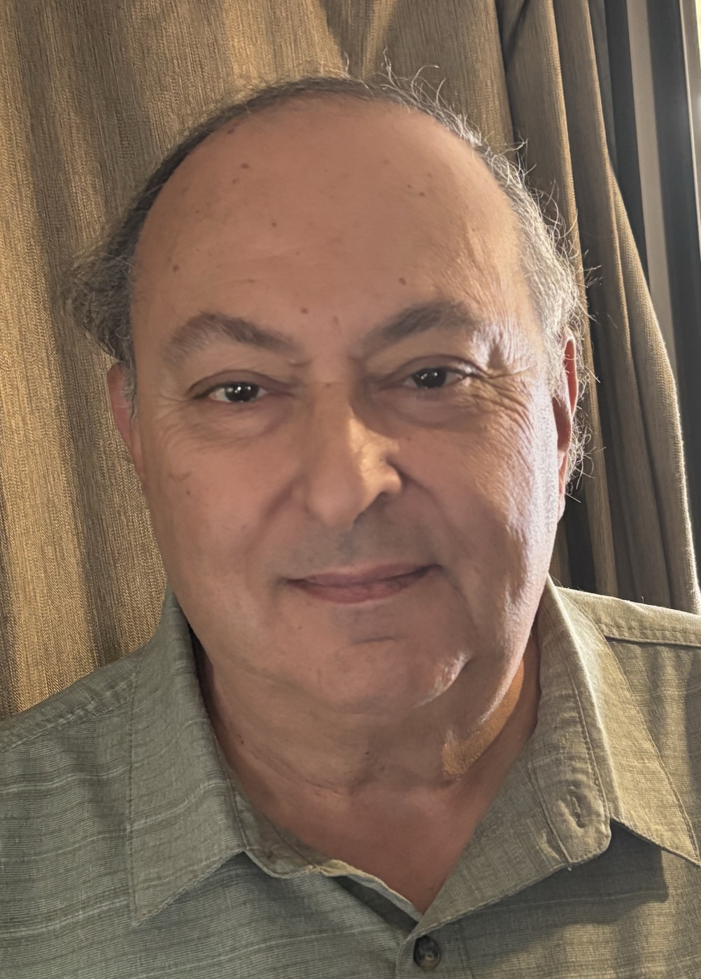 Portrait of Russ Drew smiling, wearing a green collared shirt